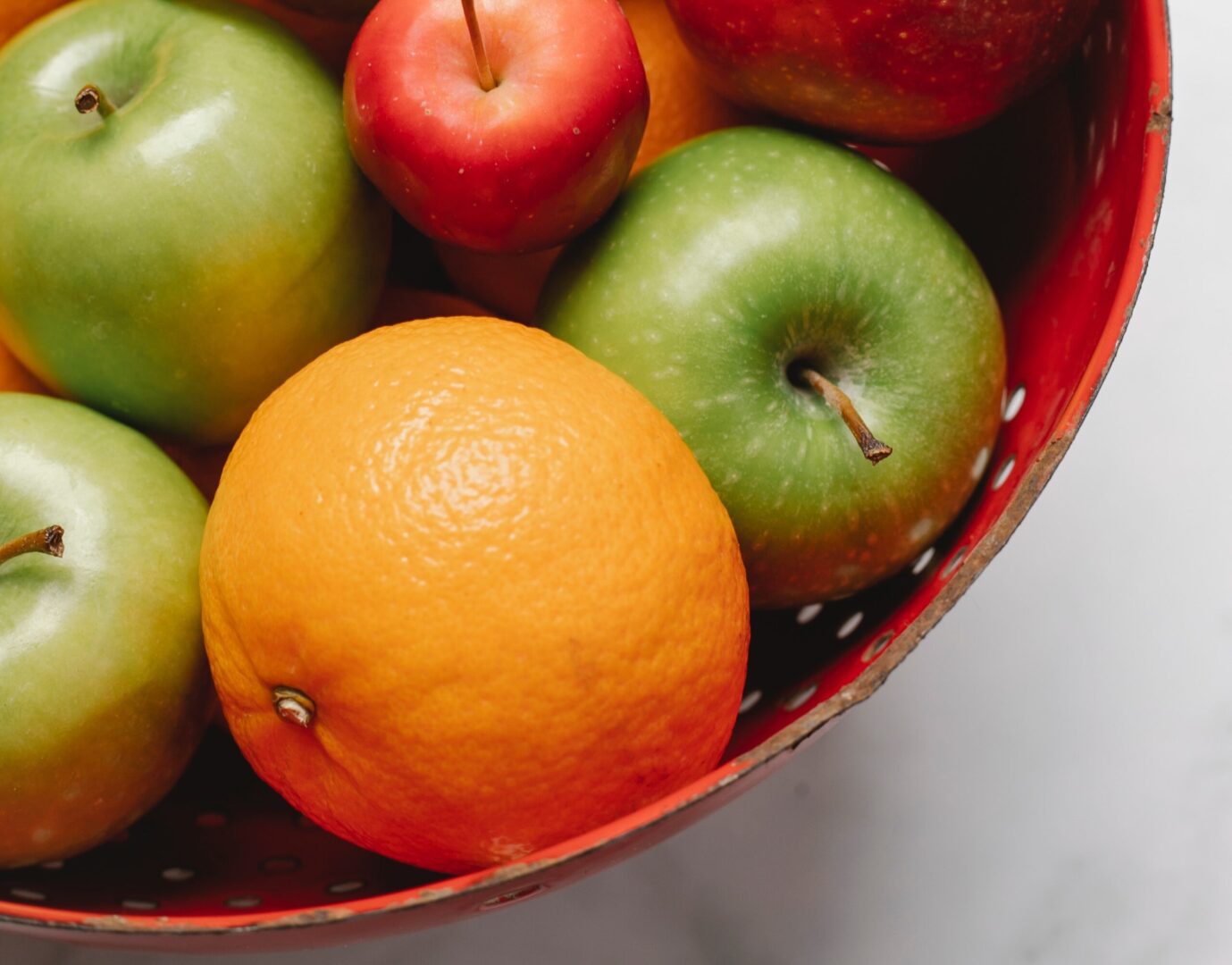 A bowl of apples and an orange