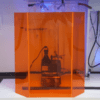 A glass case with an orange bottle and some wires